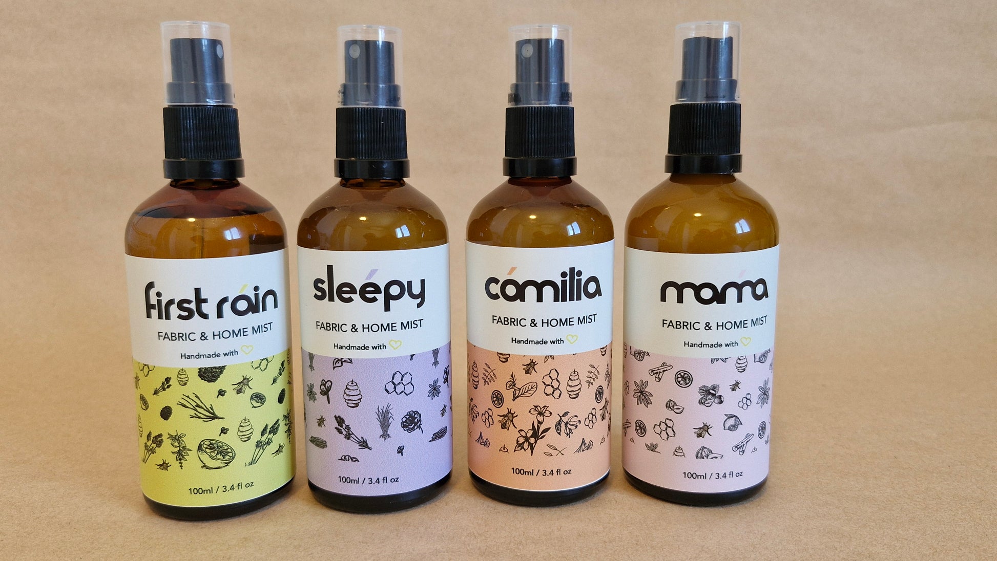 Four bottles of fabric and home mist sprays with labels on a beige background
