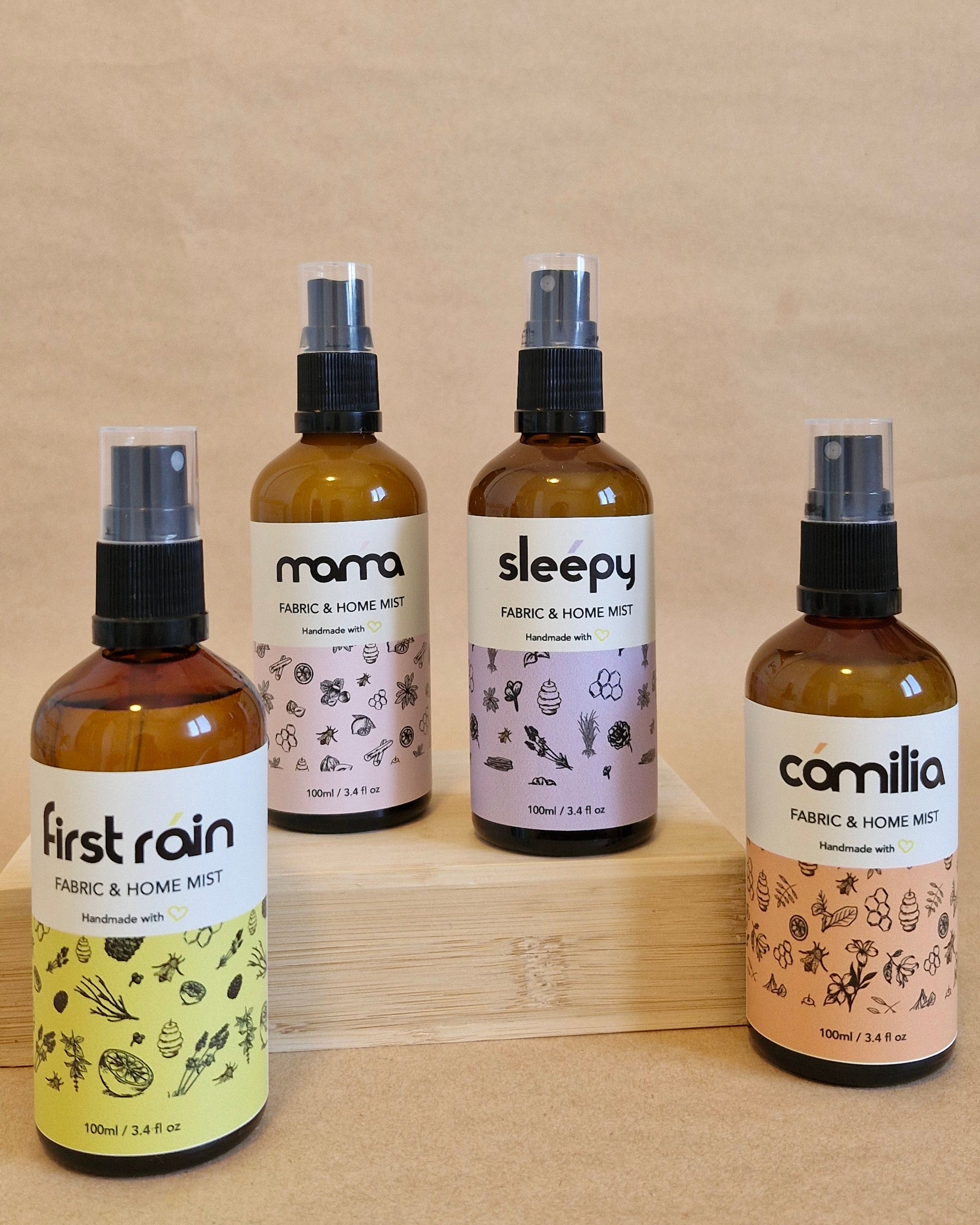 Four fabric mist bottles with labels on a beige background