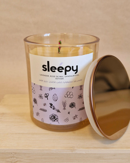 Candle labeled 'sleepy' with a decorative label on a wooden surface