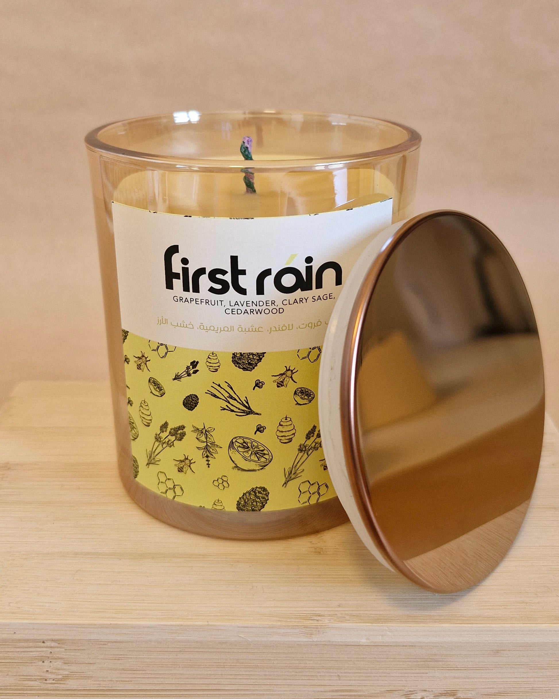 Candle labeled 'first rain' with a patterned label on a wooden surface