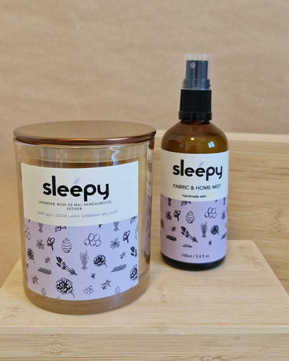 Sleepy bottle and candle jar on a wooden surface